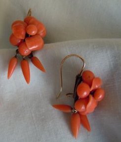 Center flower with four carved petals, within rings of coral beads